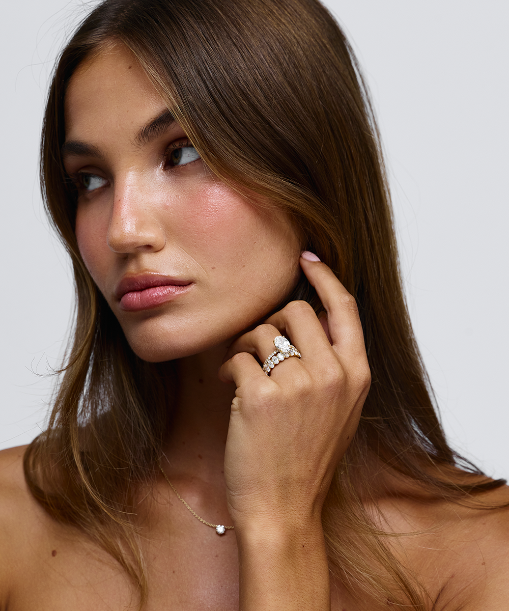 Side view of woman wearing Grace oval diamond ring showing warm 18ct yellow gold texture