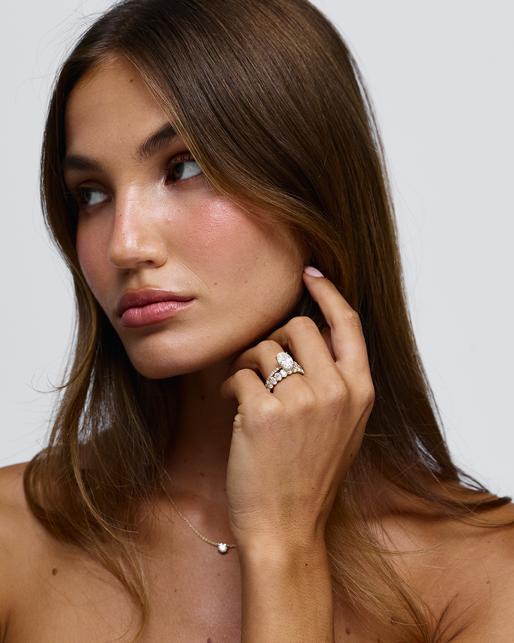 Side view of woman wearing Grace oval diamond ring showing warm 18ct yellow gold texture