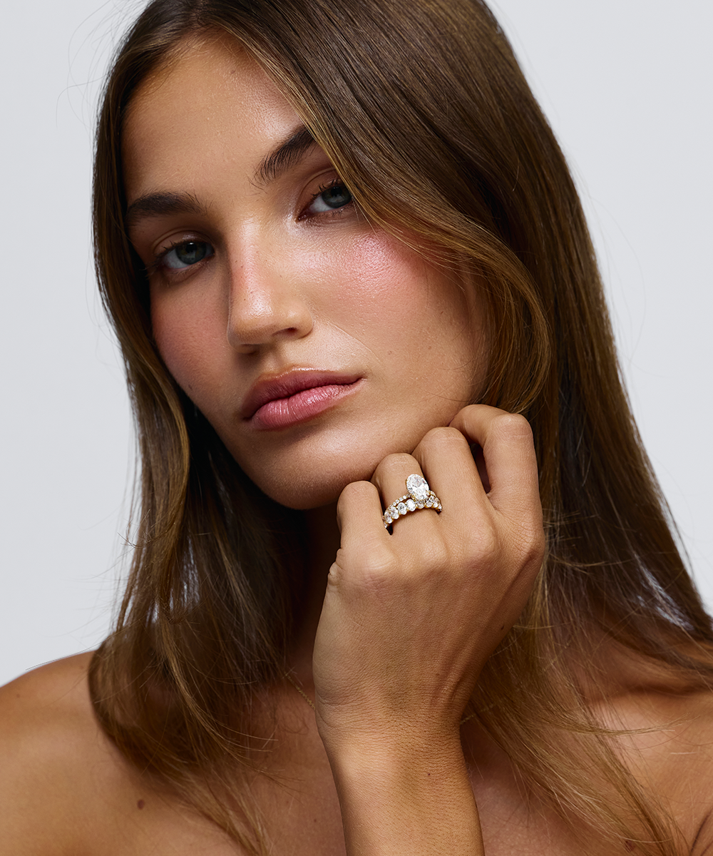 Grace oval diamond engagement ring on hand with 18ct yellow gold bead and claw set band