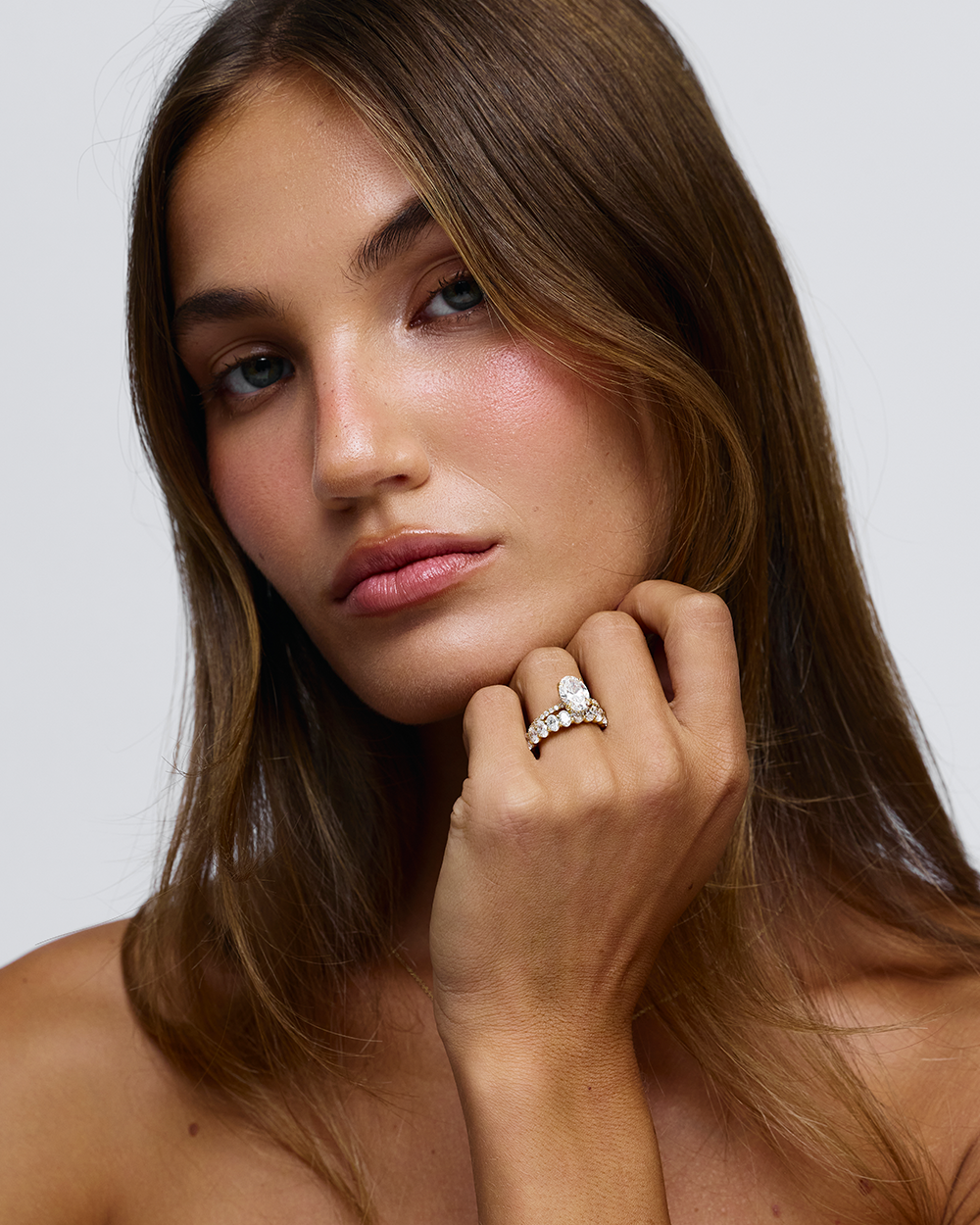 Grace oval diamond engagement ring on hand with 18ct yellow gold bead and claw set band