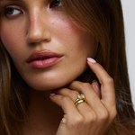 Woman wearing east west emerald cut diamond ring paired with simple gold wedding band