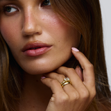 Woman wearing east west emerald cut diamond ring paired with simple gold wedding band