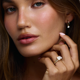 Woman wearing Nova radiant and pear diamond engagement ring with sunlight reflecting off facets in yellow gold
