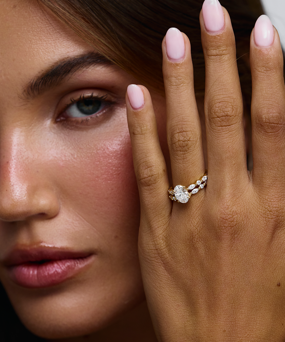 Woman wearing Kaylee oval diamond ring near cheek showing 18ct yellow gold setting