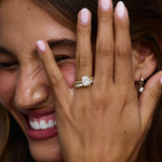 Smiling woman showing 18ct yellow gold cushion cut engagement ring with diamond band on finger