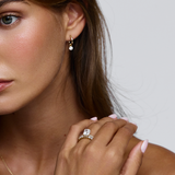 Woman wearing 18ct yellow gold solitaire engagement ring near collarbone with diamond hoop earring