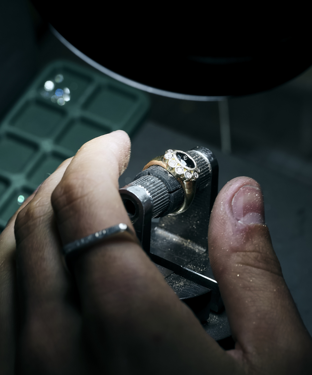 Jeweler holding Ophelia Pinky Ring with dark stone and chunky signet band