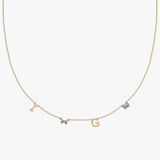 Solid gold personalized charm necklace with initials I and G, butterfly birthstone, and blue gem