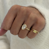 18ct yellow gold oval diamond bezel ring worn on index finger with fluffy white sweater background