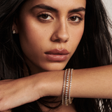 Model wearing layered yellow gold tennis bracelets with matching stud earrings