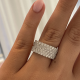 Silver ring with diamonds on a person's finger against a neutral background