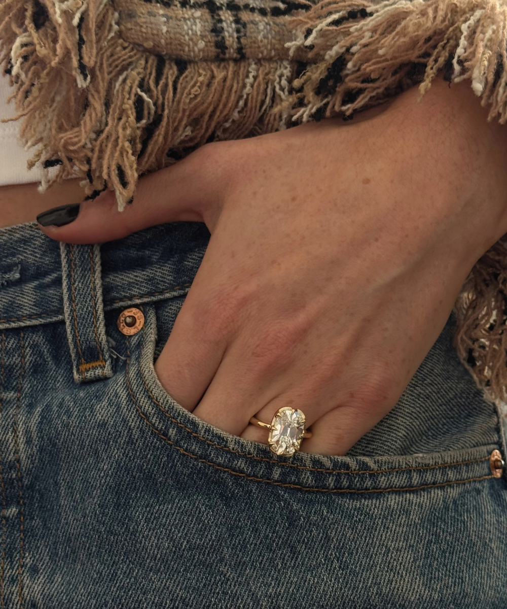 Yellow gold solitaire diamond ring worn with blue denim jeans and black nail polish