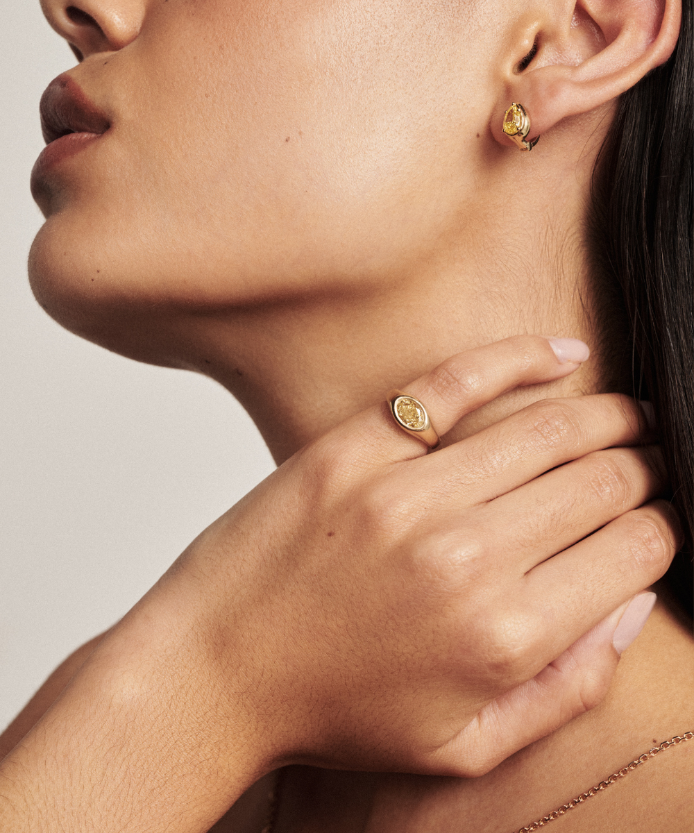 Side profile of pear yellow diamond huggie earring with signet ring