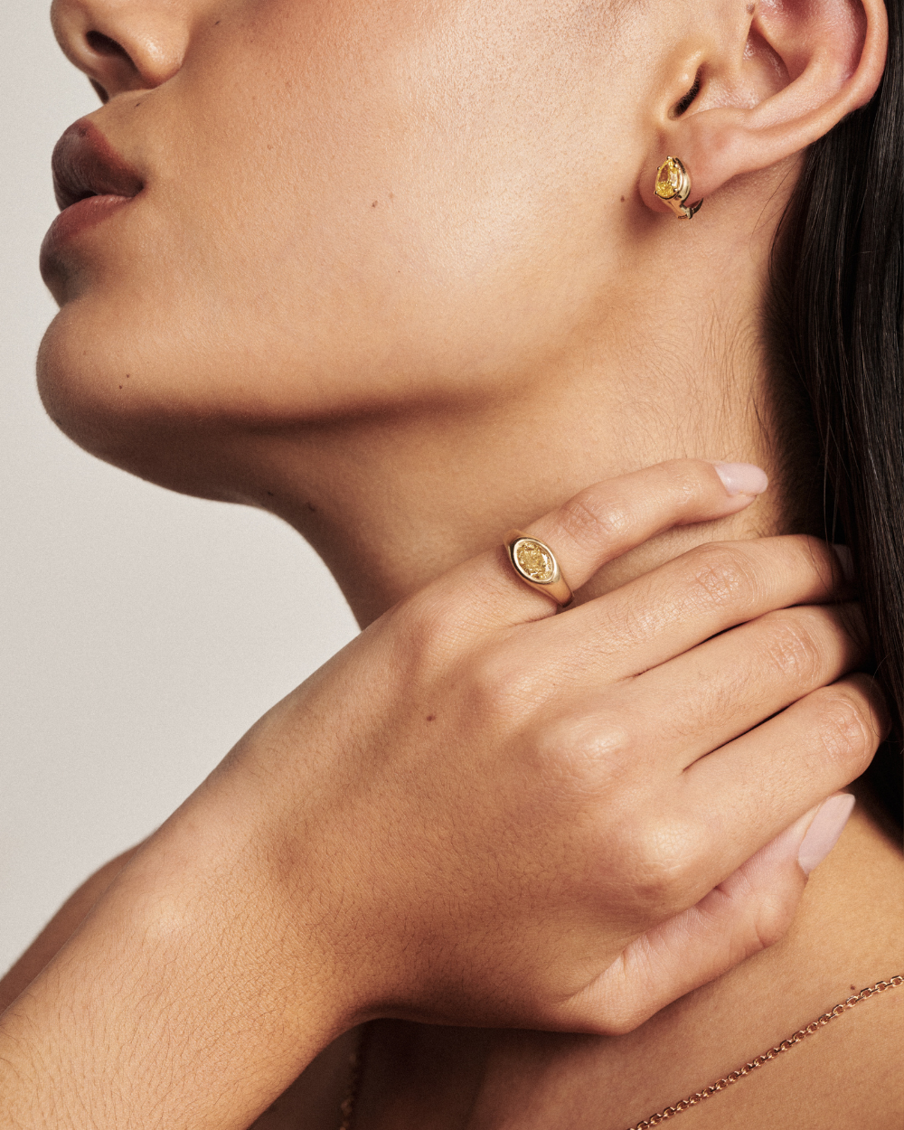 Side profile of pear yellow diamond huggie earring with signet ring