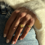 Layered yellow diamond rings on denim with knit sweater sleeve