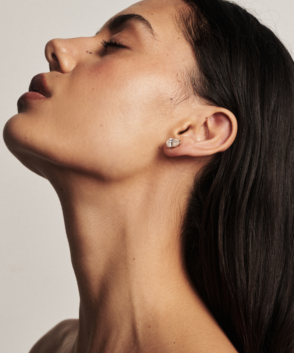Side profile of white gold pear diamond stud following natural ear curve