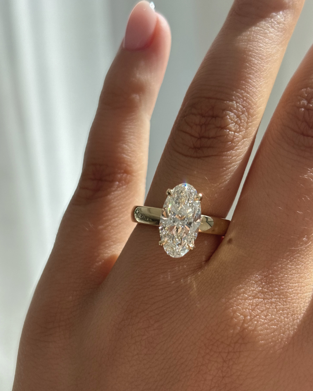 Harper oval lab grown diamond engagement ring on hand with 18ct yellow gold claw setting
