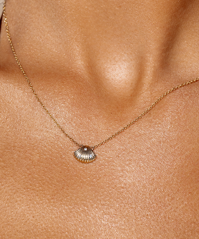 Close-up of 9ct gold Venus seashell pendant with diamond on neck