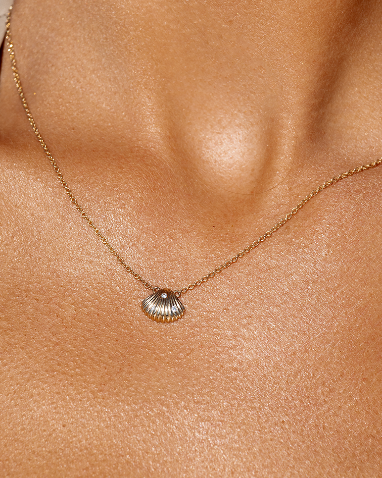 Close-up of 9ct gold Venus seashell pendant with diamond on neck