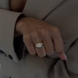 Woman wearing Lucie pear diamond engagement ring on hand with textured suit sleeve