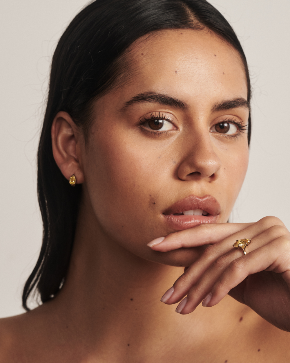 Woman wearing pear yellow diamond huggie earrings with matching ring