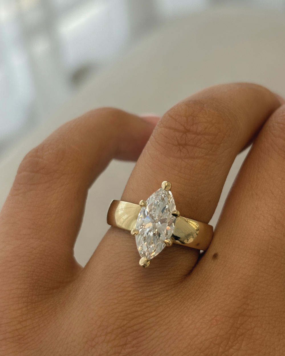 Close-up of tapered 18ct yellow gold band and four-prong marquise diamond setting