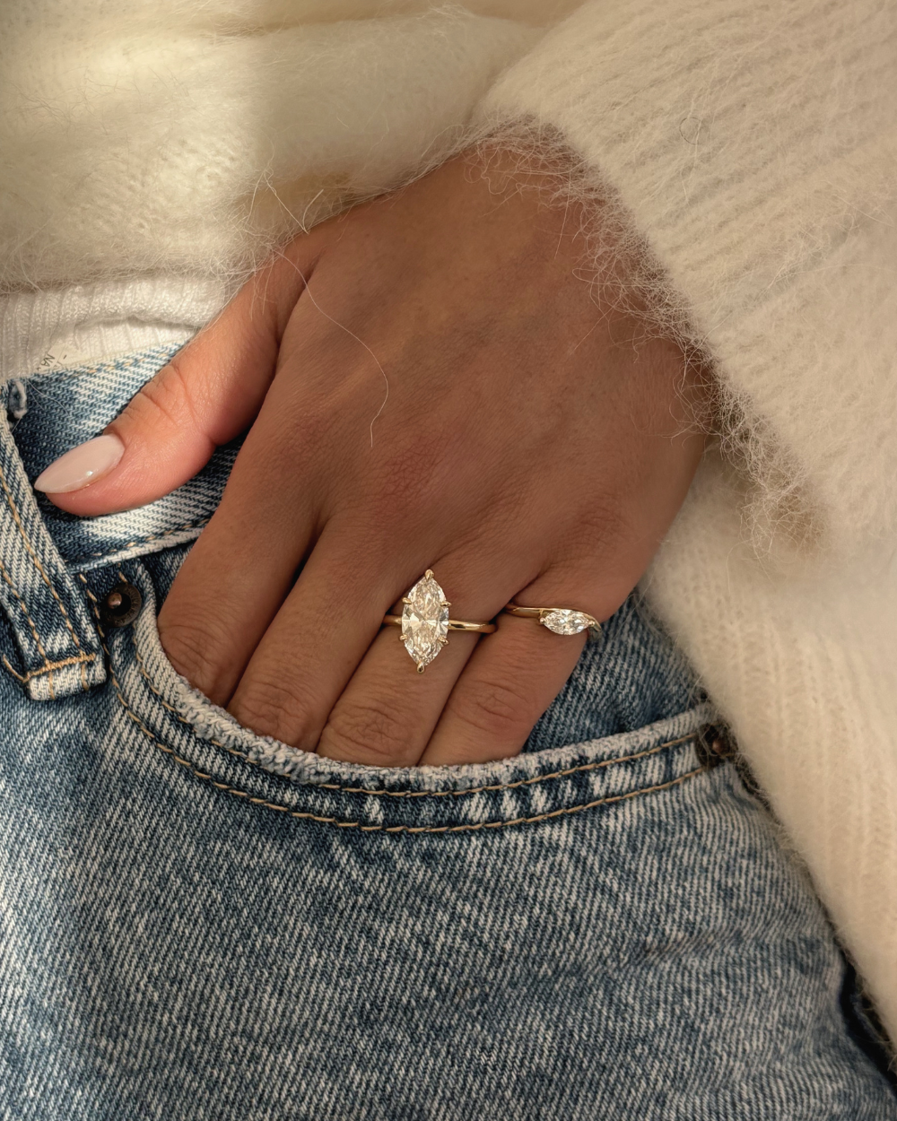 Marquise diamond engagement ring stacked with matching band on denim pocket hand