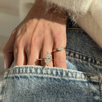 Sunlit lifestyle shot of marquise solitaire ring paired with thinner band on hand