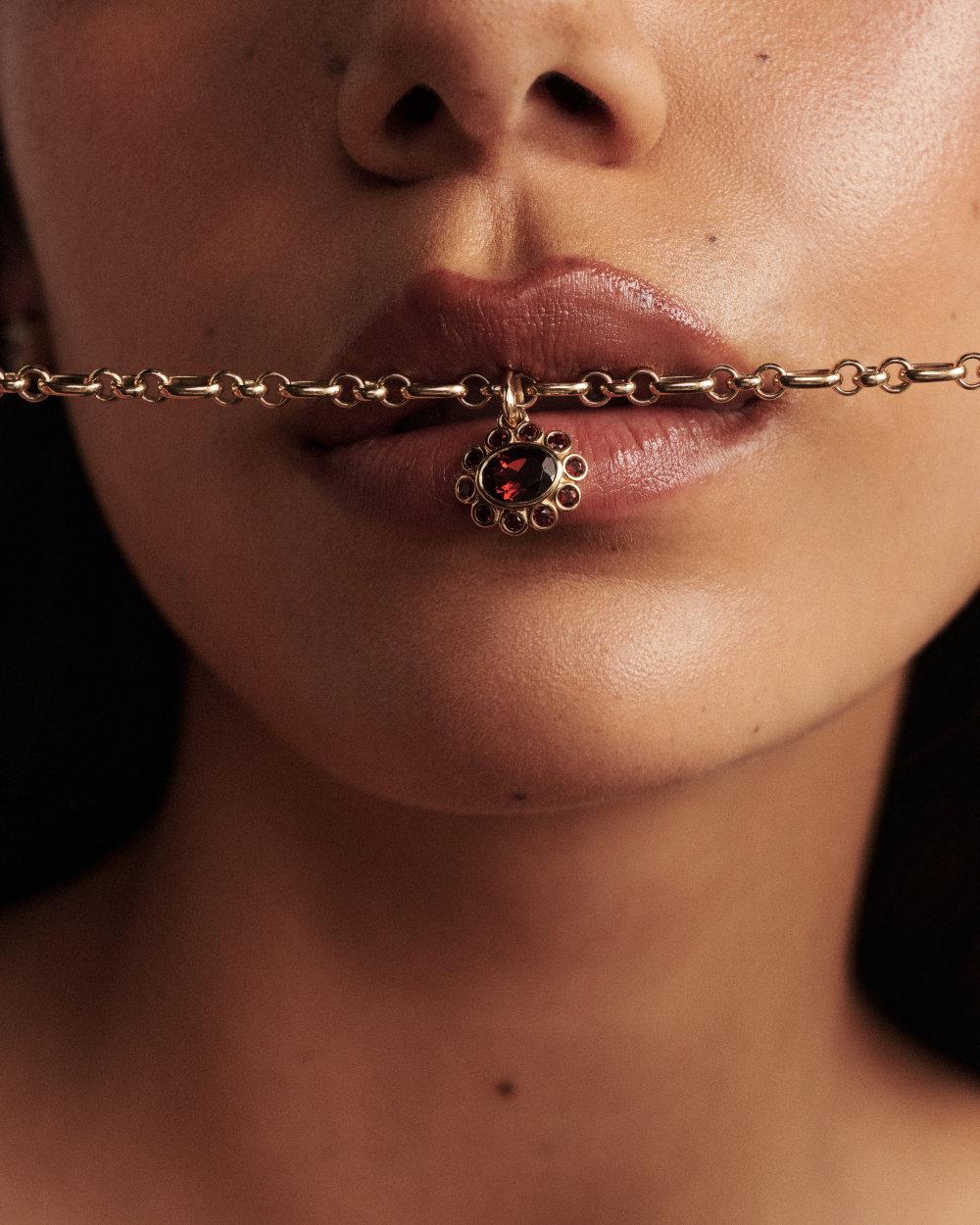 Close-up of 9ct yellow gold belcher chain with red floral pendant detail