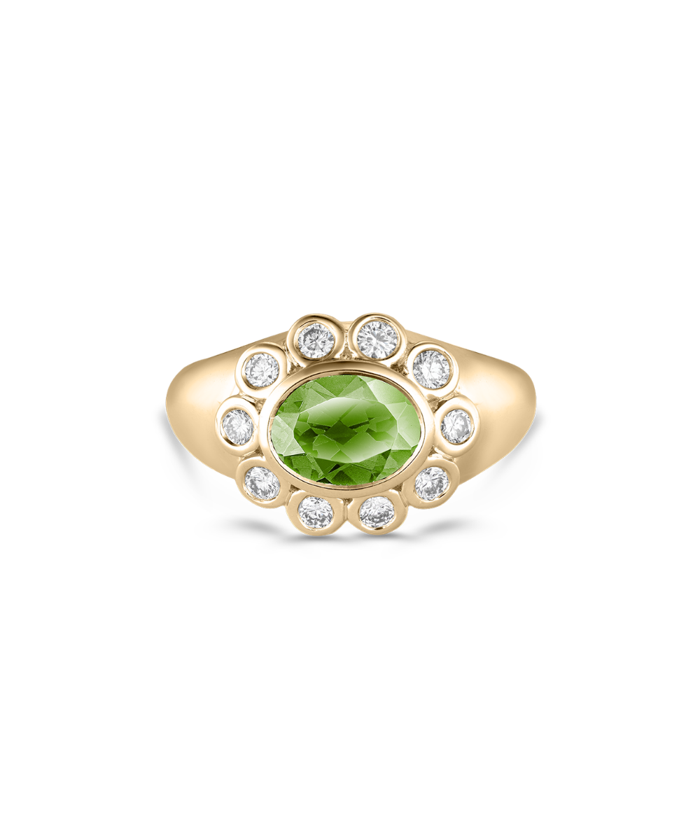 A yellow gold ring featuring a central oval green peridot gemstone surrounded by a halo of small round clear diamonds, set against a plain white background.