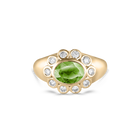 A yellow gold ring featuring a central oval green peridot gemstone surrounded by a halo of small round clear diamonds, set against a plain white background.