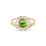 A yellow gold ring featuring a central oval green peridot gemstone surrounded by a halo of small round clear diamonds, set against a plain white background.
