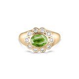 A yellow gold ring featuring a central oval green peridot gemstone surrounded by a halo of small round clear diamonds, set against a plain white background.