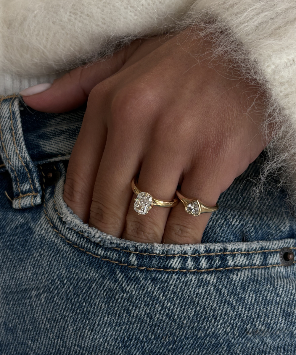 woman wearing 18ct yellow gold cushion cut diamond engagement ring on denim jeans hand