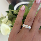 Close-up of woman wearing Portia trilogy ring with pink manicured nails showing real-life wearability of 18ct yellow gold