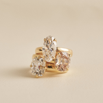 Stacked yellow gold rings featuring clear and light brown oval diamonds