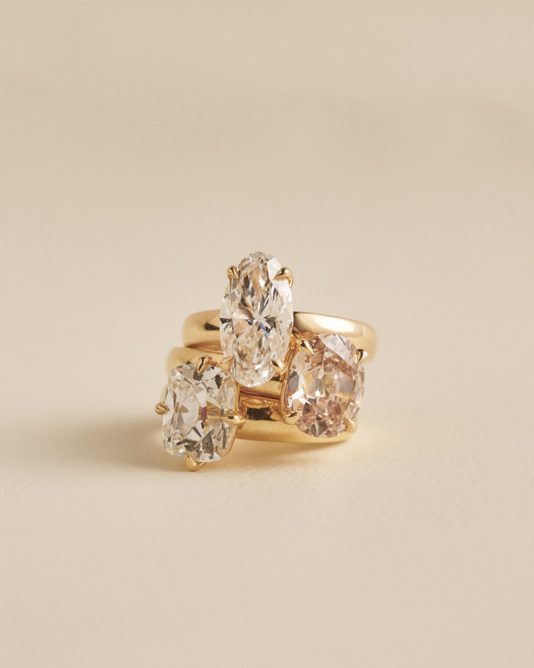 Stacked yellow gold rings featuring clear and light brown oval diamonds