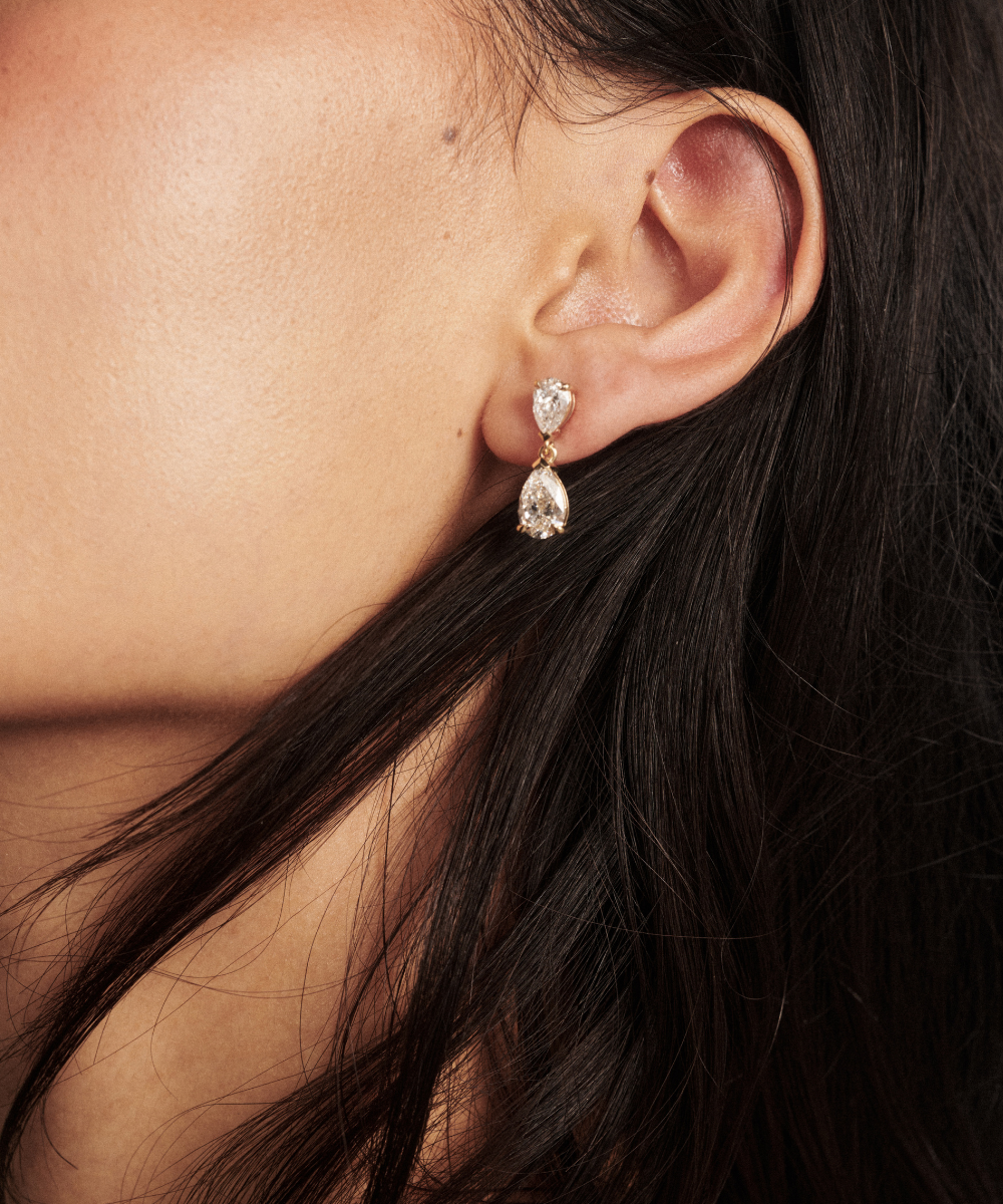 Side profile of woman wearing yellow gold pear shaped diamond drop earring