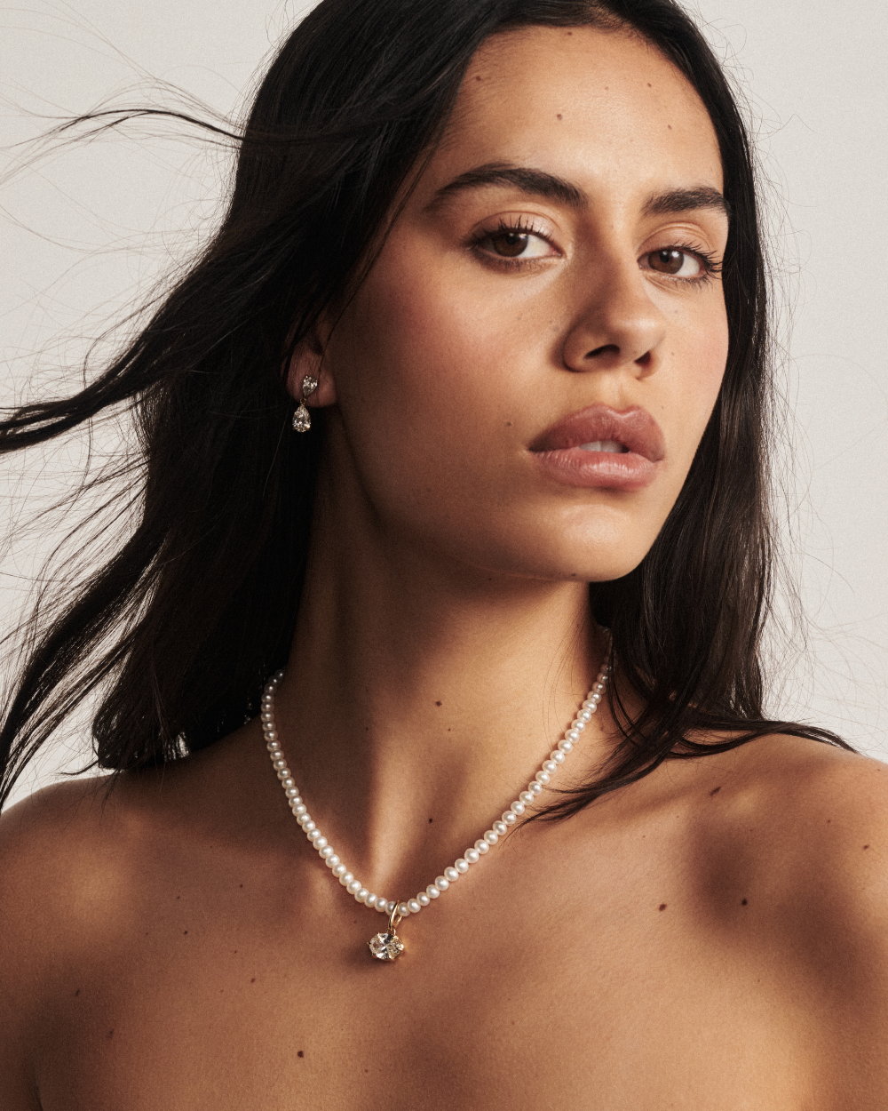Woman wearing pearl necklace with small oval gold pendant