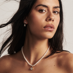 Woman wearing pearl necklace with small oval gold pendant