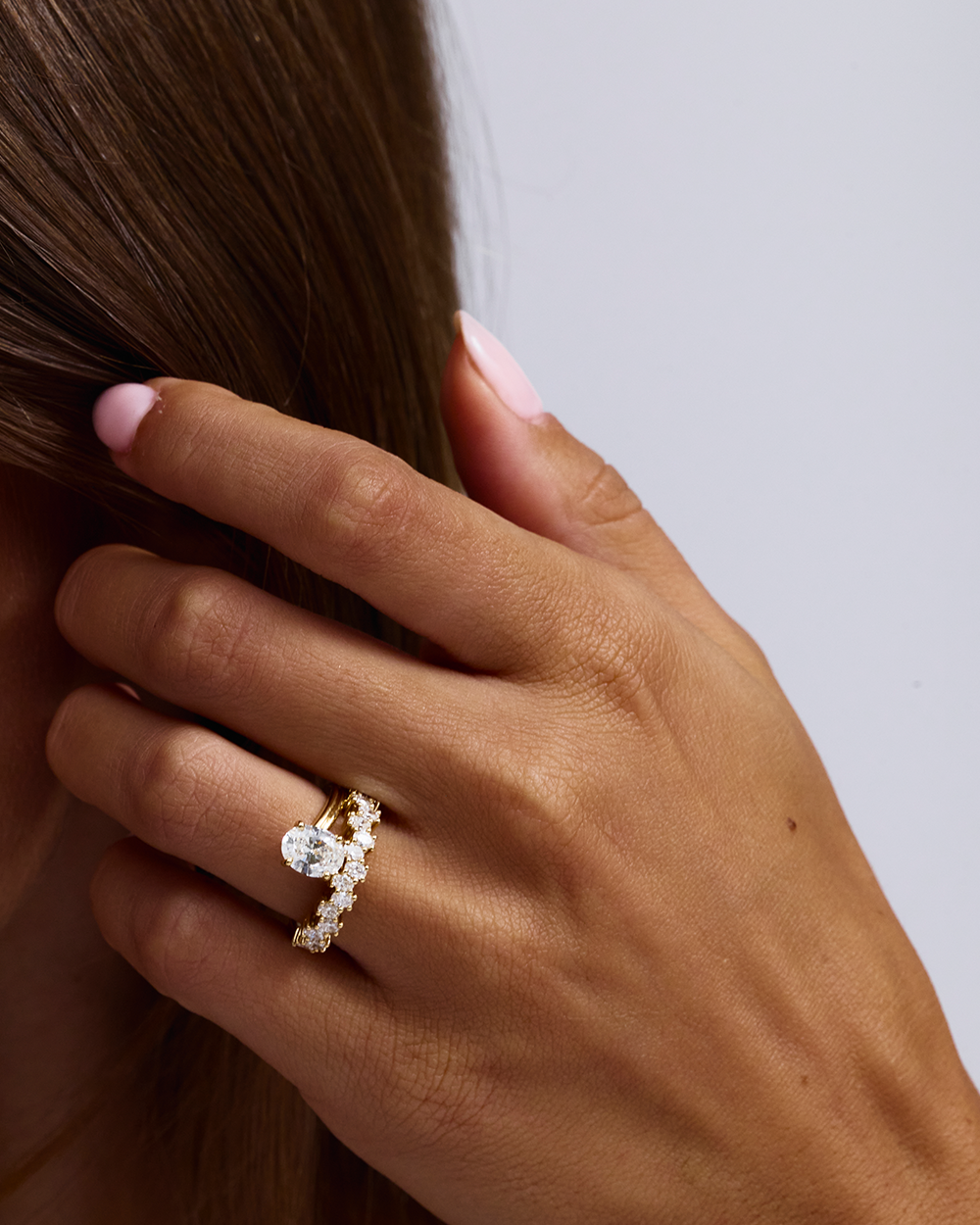 18ct yellow gold oval diamond engagement ring with asymmetrical 15-stone channel band on hand