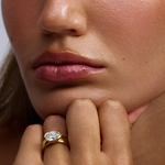 Close-up of Arabella east-west oval diamond ring on finger against jawline