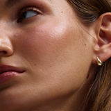 Small asymmetrical gold teardrop earring on model ear