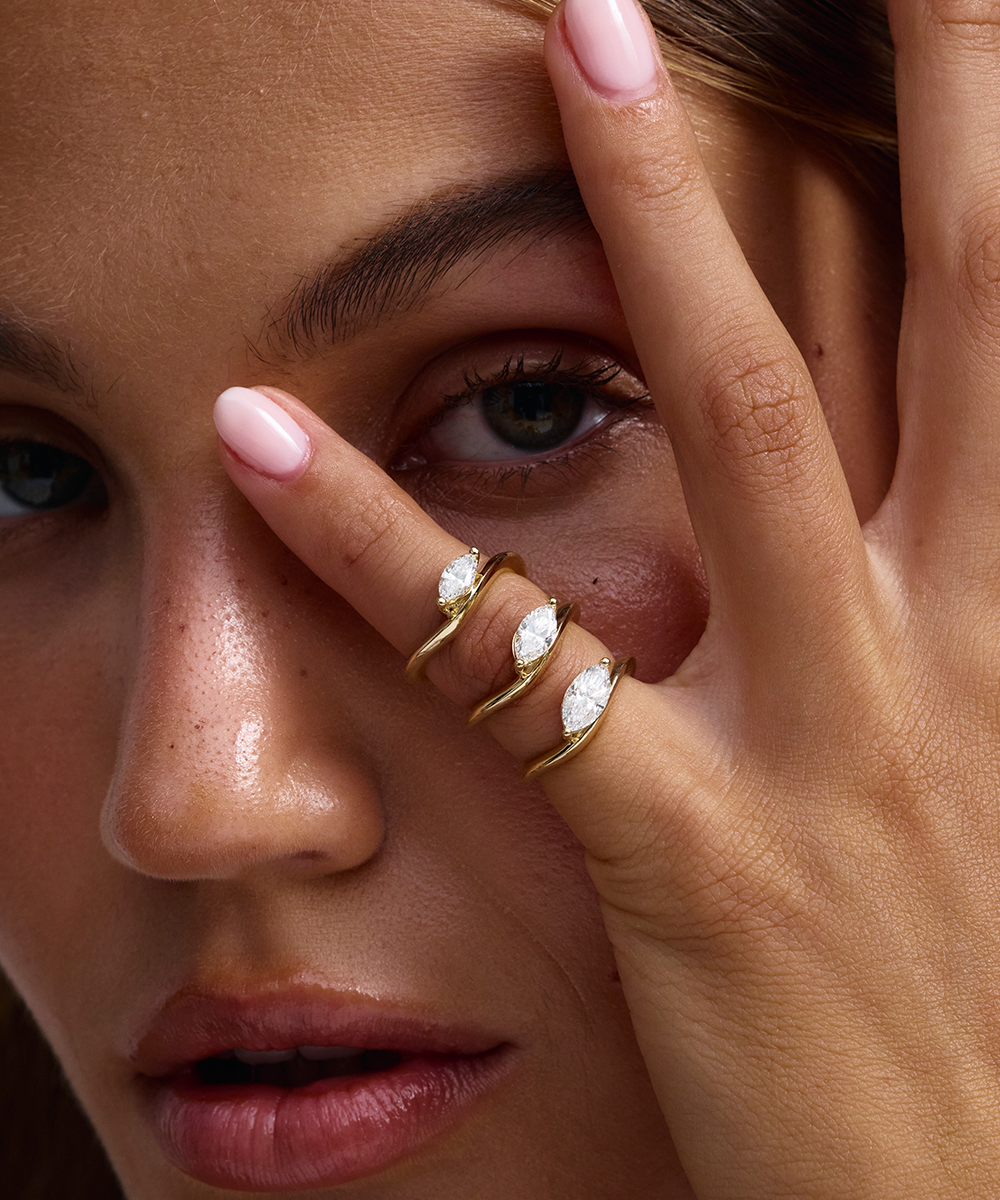 Three stacked yellow gold marquise diamond pinky rings on hand
