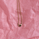 Organic shaped gold heart pendant necklace on pink paper