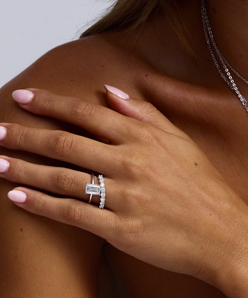 White gold emerald cut diamond ring with side diamonds on model hand