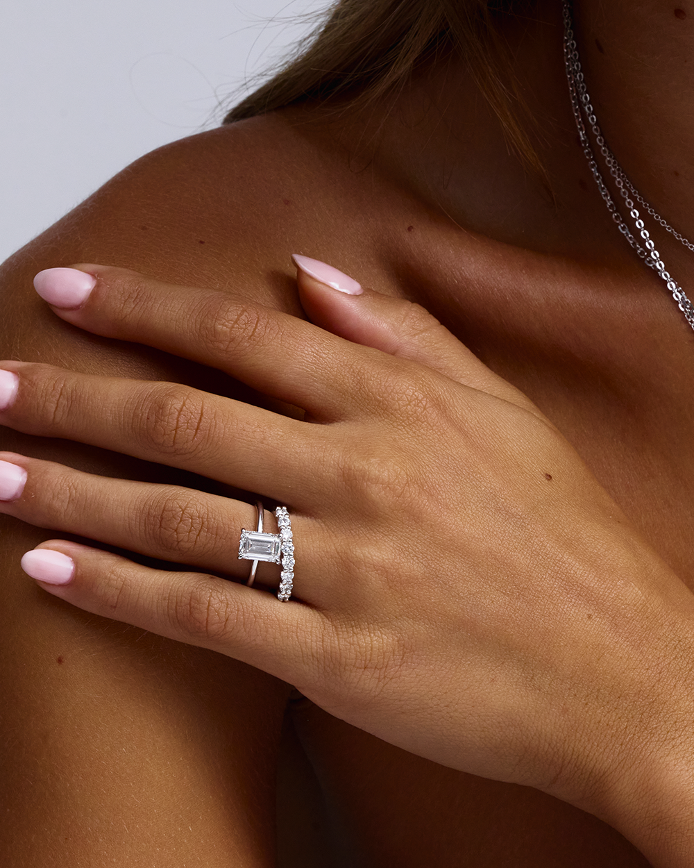 White gold emerald cut diamond ring with side diamonds on model hand
