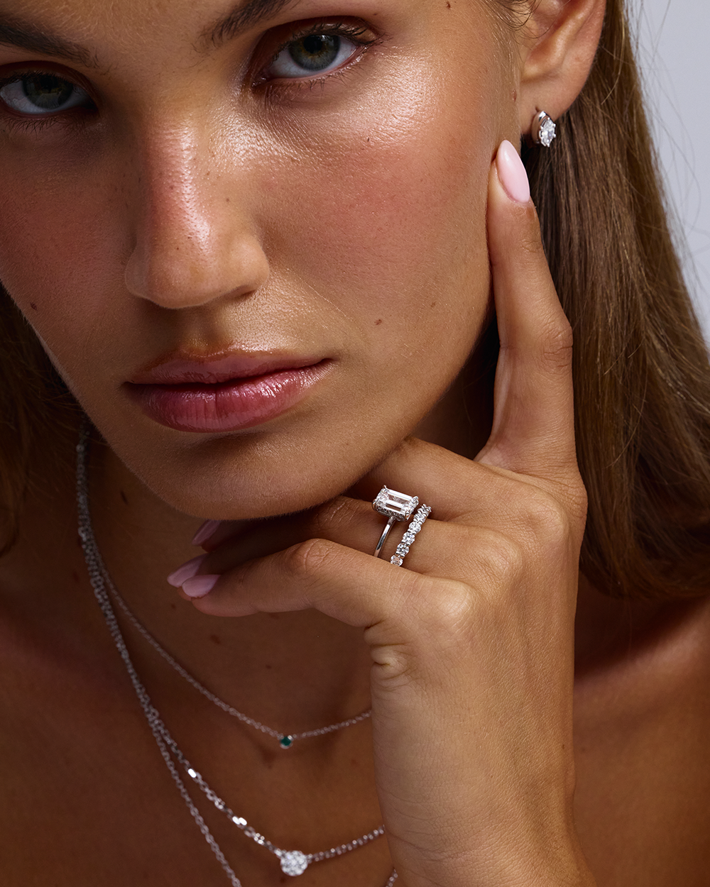 Model wearing emerald cut solitaire ring and marquise stud earrings