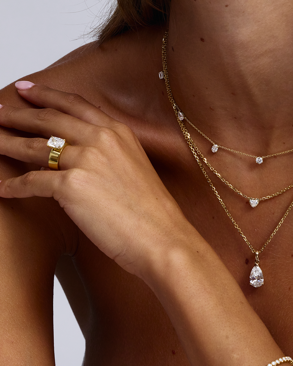 Cushion cut diamond solitaire engagement ring styled with layered gold necklaces