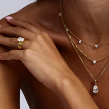 Cushion cut diamond solitaire engagement ring styled with layered gold necklaces